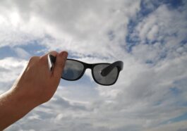 Sonnenbrille wird in Richtung Wolken gehalten