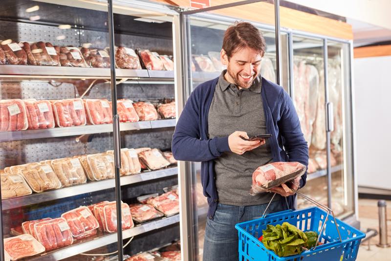 Mann nutzt Discounter-App im Supermarkt